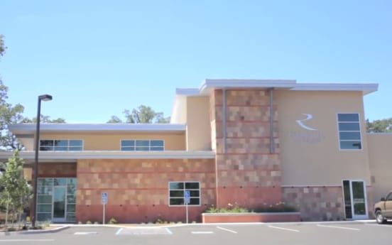 The Riverside Oral Surgery building at 316 Knollcrest Drive, a modern two-story office with a stone tower and the R logo